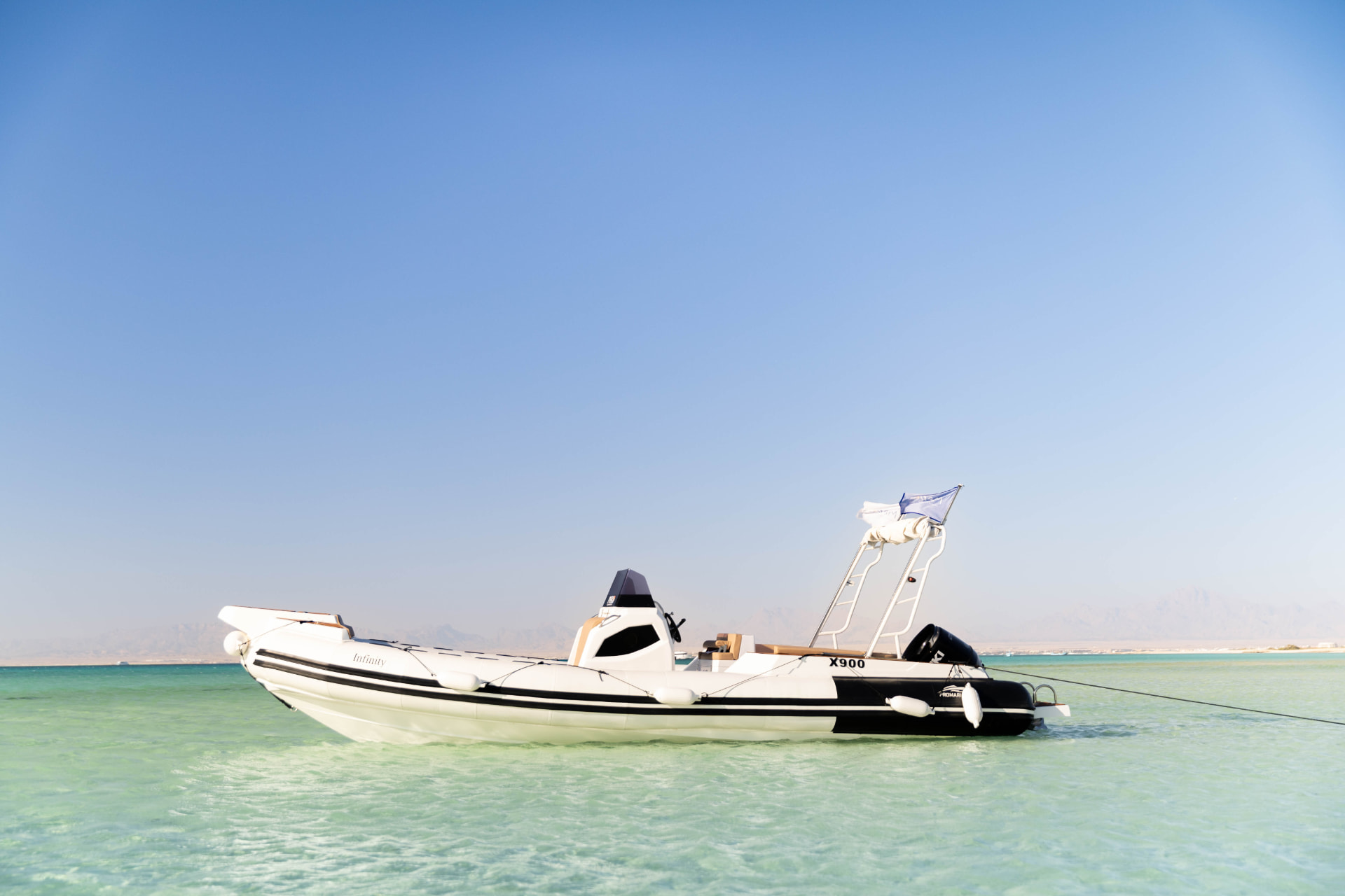 Das Speedboot Infinity vor Anker im flachen, türkisfarbenen Wasser