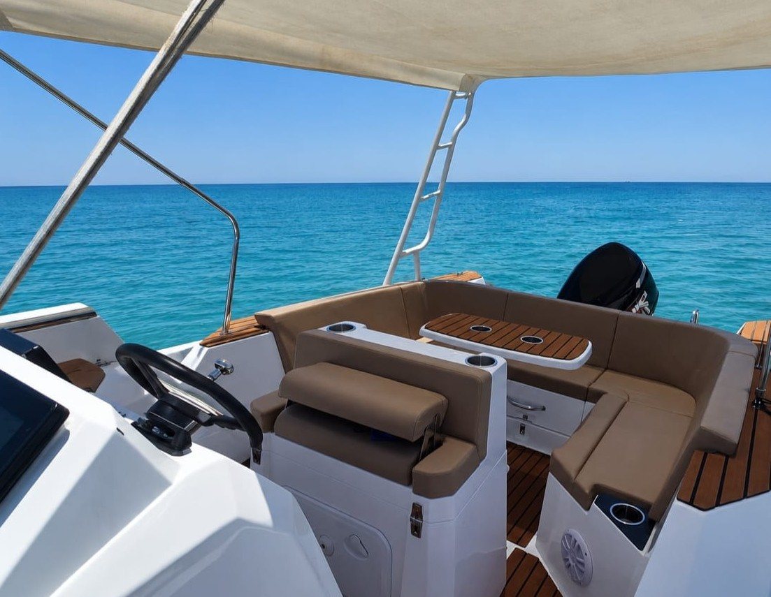 Onboard view of the Maro Redsea Promarine X900 showing the helm, shaded cushioned seating, teak table and the turquoise Red Sea beyond