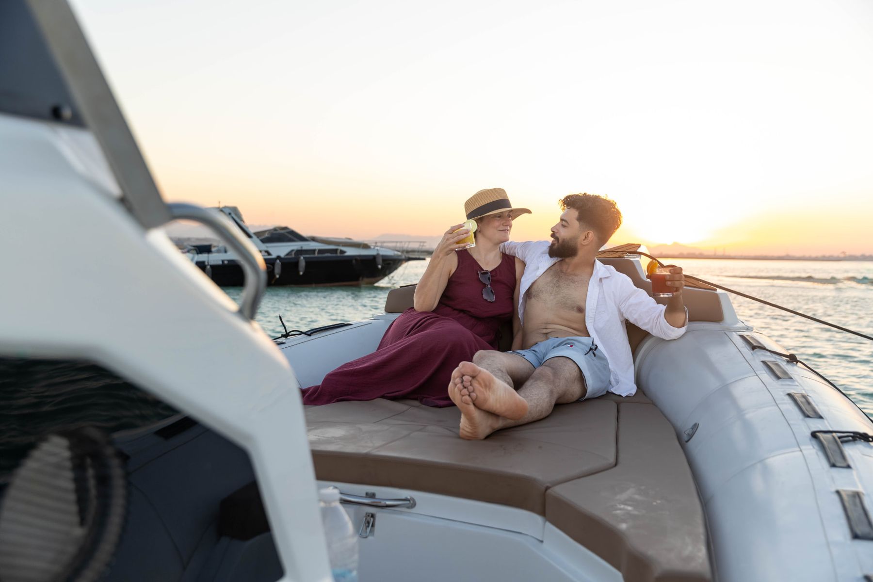 Guests relaxing with drinks on the cushioned rear sunbed of the Promarine X900 at sunset